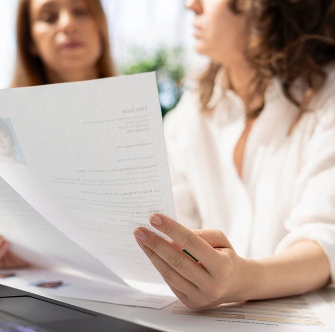 Două femei examinează un document tipărit