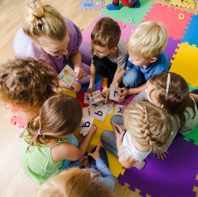 Children playing together on a colourful mat at kindergarten
